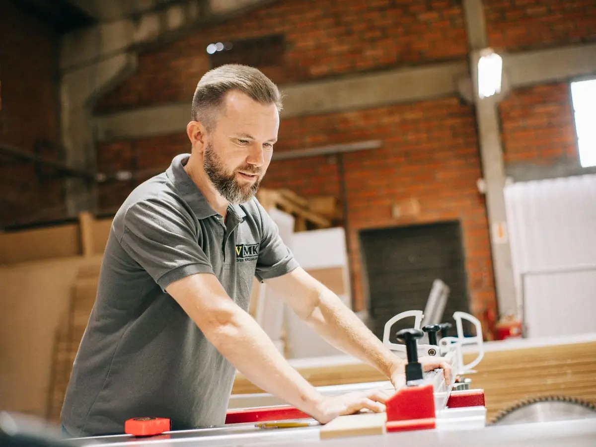 Un menuisier prend ses mesures dans son atelier