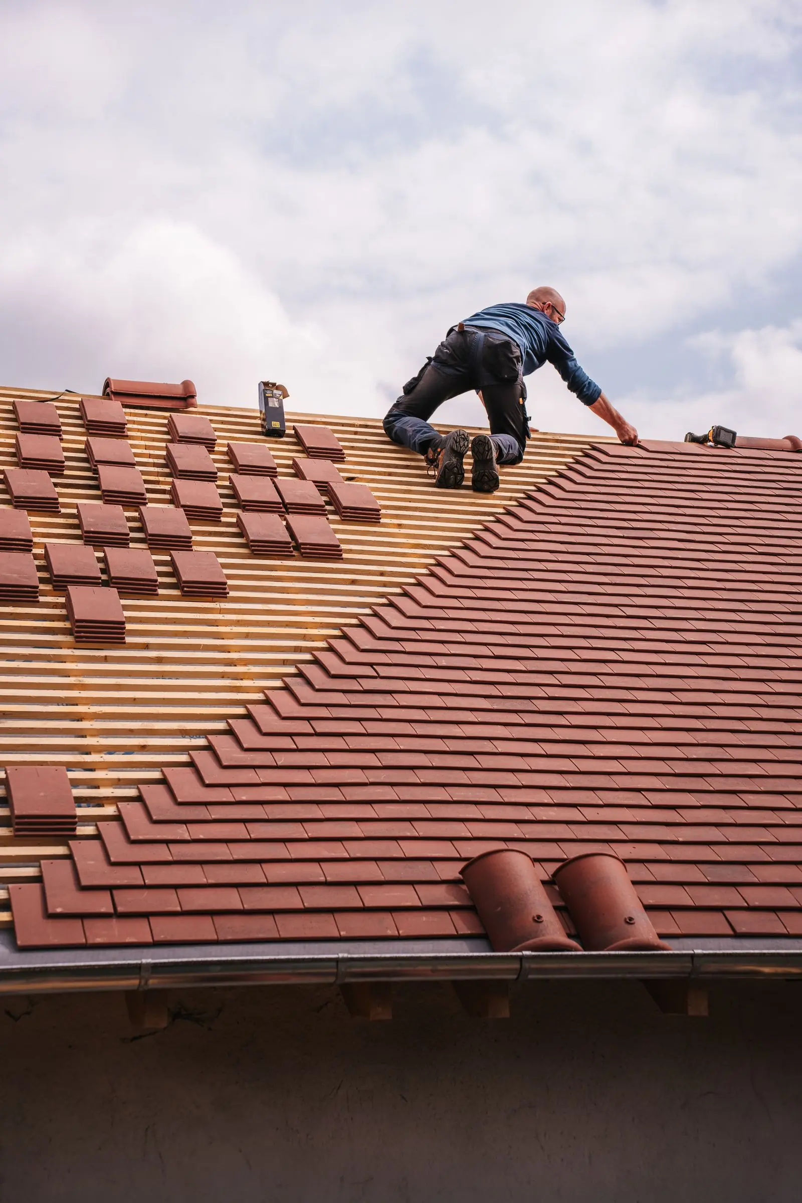 Un couvreur pose des tuiles sur une toiture
